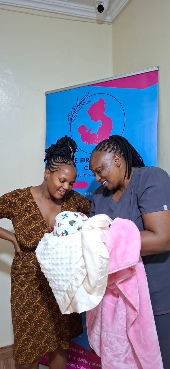 A Divine Birth midwife holding a swaddled newborn at the centre
