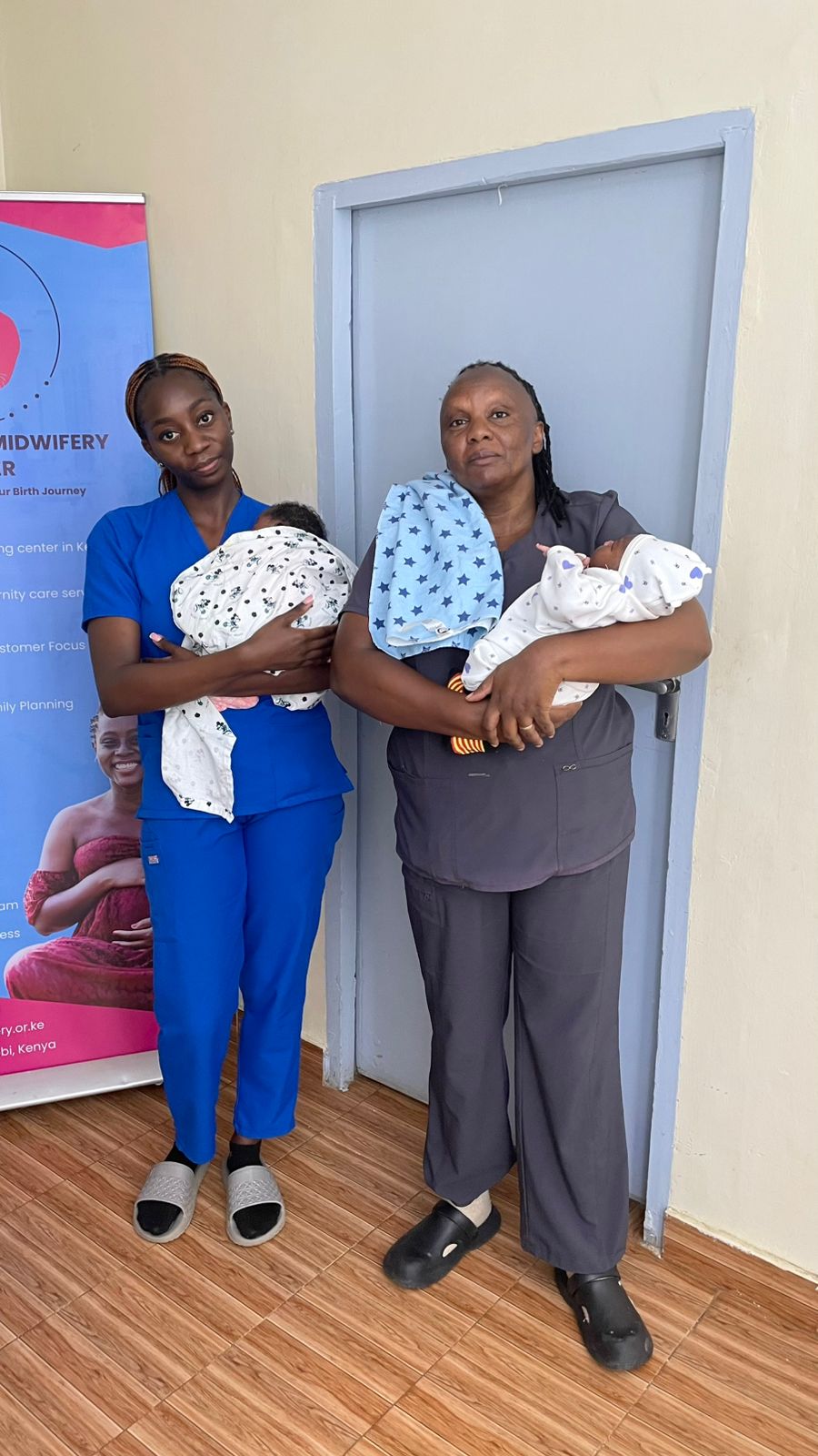 Two Divine Birth midwives each holding a newborn twin